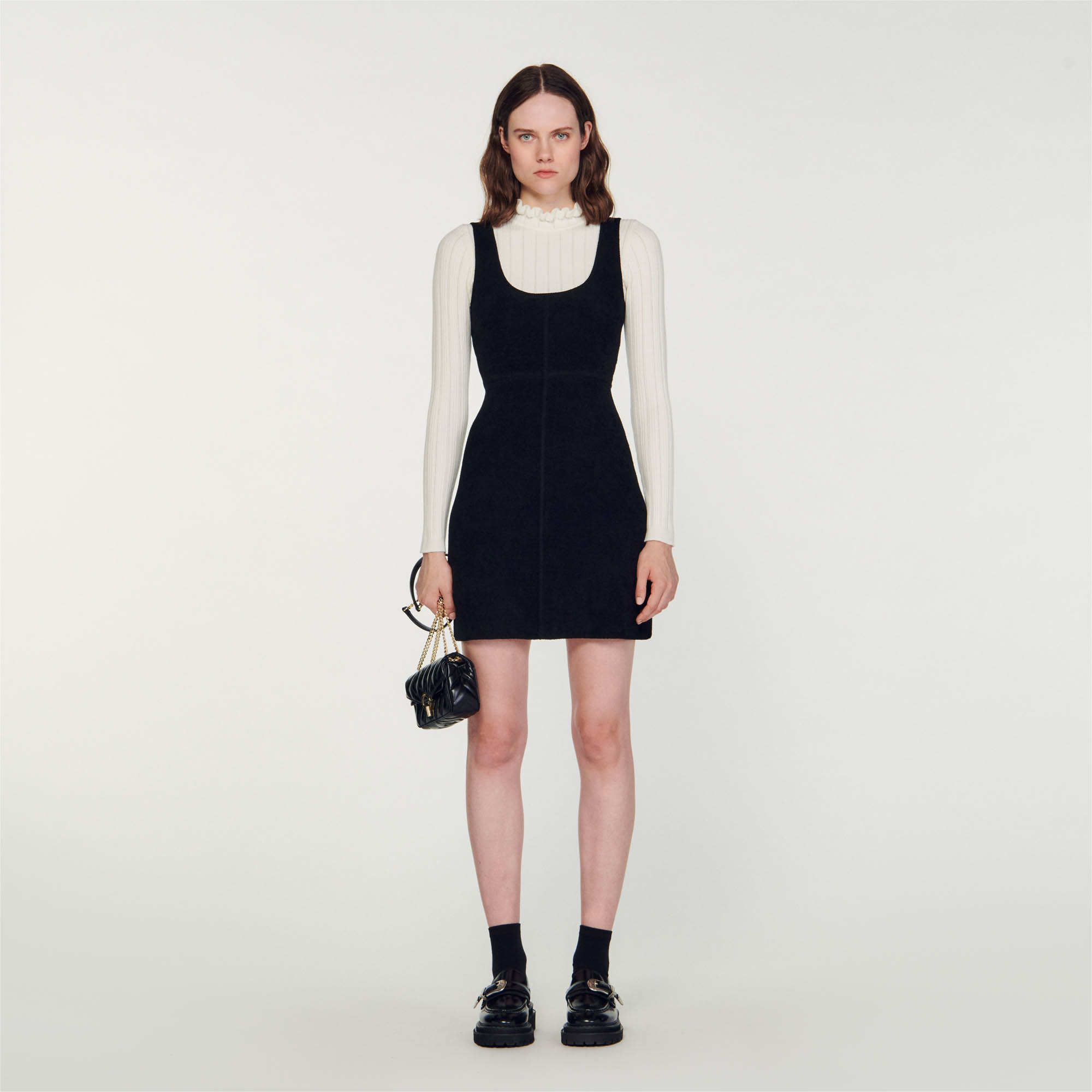 Sandro acrylic 2-in-1 effect pinafore dress in two-tone knit featuring a tight-fitting top with ruffled high neck and long sleeves and a layered velvet dress on top with flat straps and scoop neck